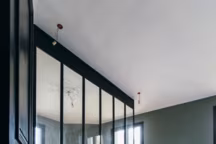 Dans la chambre parentale la décoration reste sommaire : deux chevets, une planche de bois comme tête de lit... La verrière et les moulures, sublimées par la couleur suffisent.