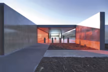 Le mur en plexiglas rouge transpercé de lumière se reflète avec féerie sur l'eau et anime le sol en béton.