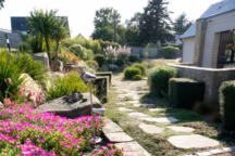 Cette allée en pas japonais (dalles de granit beiges) s'harmonise parfaitement avec le décor végétal tout en naturel. Réalisation Eric Lequertier.