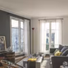 Le salon offre plusieurs vues sur Montmartre. Canapé, tapis en laine, voilage et table basse, Caravane ; lampadaire d'Ettore Sottsass chez Artemide ; meuble TV et fauteuil en osier chinés.
