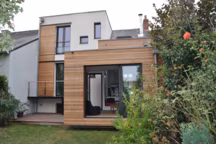 Extension bois (en rez-de-chaussée) et surélévation bois de l'étage (enduit). On devine, au dessus de l'extension, la toiture d'origine. Bardage bois (red cedar) et menuiseries aluminium.