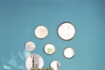 Sur le bleu lumineux du salon, (réf. 26 C 04, The Little Greene), les anciens plateaux de bistrots années 50 font office de miroirs ! Fauteuil " Kaar » en khadi de coton motif pied-de-poule ; table basse " Atoll » en acier patiné, le tout Caravane.