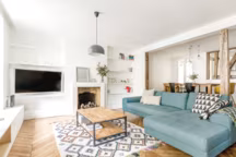 Canapé d'angle bleu Made.com, table basse du couple entre métal et bois, suspension Normann Copenhagen et tapis esprit berbère.