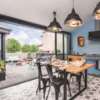 Dans cette cuisine à l'esprit maison de campagne, les suspensions en aluminium Habitat s'intégrent parfaitement. Sur la terrasse, des meubles outdoor Fermob.