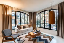 Fauteuil vintage La Redoute, table basse La Redoute, tapis Joseph Lebon, canapé Hôtel Megastore, coussins Dutch Decor, rideaux sur mesure gris taupe, sac de frappe Maison du Monde