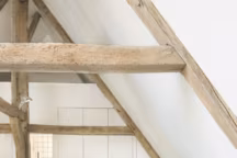 Chaque chambre a son style. Sous les toits, le lit mêle draps en lin, Lissoy, plaid en laine Brun de Vian Tiran et coussins The Conran Shop. Table de chevet en béton et métal, Géraldine Perrie-Doron. Fauteuil Airborne avec housse Lhassa en agneau du Tibet. Peau de vache chinée.