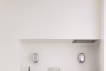 La cuisine ouverte en patchwork de marbres, avec ses appliques "Chevalière" en aluminium poli. Sur la table à plateau laqué entourée de chaises "Mobilor" de René Herbst, coupe en métal argenté et albâtre, édtition Christofle.