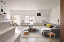 Au premier niveau, après l'escalier qui marque la transition avec la cuisine, le salonsalle à manger. L'espace a été entièrement ouvert pour laisser place à un plateau unique et lumineux. Sous les fenêtres, un rangement bas, fabriqué sur mesure, court tout le long du mur. Sur la droite, un canapé modulable " Mags » et des coussins " Dot », Hay. Au premier plan, lampadaire " Cord », Form Us With Love pour Design Stockholm House et, dans le fond, lampadaire " Twiggy » noir de Marc Sadler, Foscarini. Sous la table basse fabriquée en bois de récupération et signée Piet Hein Eek, un tapis en laine signé Patricia Urquiola, Gan.