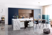 Façades Kiffa bleu de minuit mat et décor noyer du Quercy structuré / Poignées Rhéa finition bronze / Plans de travail stratifié marbre de Luni mat et noyer du Quercy structuré / Meubles sur mesure façade bleu de minuit mat / Poignées Taktil encastrées finition inox. A partir de 5 520 euros. Mobalpa.