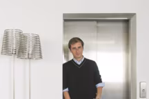 Philippe Nigro dans le showroom parisien de Ligne Roset, 85, rue du Bac (VIIe). Le designer a pris la pose près du lampadaire " Stripes », qu'il a dessiné pour l'éditeur de mobilier avec deux abat-jour qui n'en forment plus qu'un. Une pièce en Inox brossé, découpée au laser.