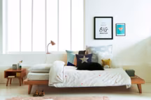 Lit Jimi en pin massif, 289 euros ; Chevet Anda en pin massif, 69 euros ; Housse de couette Edots en percale pur coton, à partir de 29 euros ; Lampe Rosella en métal, 39 euros ; Housses de coussin, à partir de 14,99 euros ; Tapis peau de mouton Livio, 99,99 euros, le tout La Redoute.