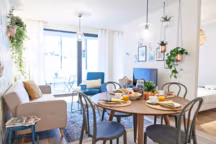 Table, chaises et étagères House Doctor. Lampes Bloomingville. Fauteuil Maisons du monde. Tapis Dutchbone. Canapé convertible Miliboo.