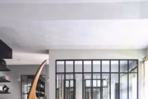 Le salon collectionne les belles pièces de design, une table basse "Elliptique" et un "Lounge Chair" de Charles & Ray Eames, un lampadaire tripode de Jacques Rispal, une banquette et des fauteuils scandinaves des années 1950, un tapis berbère ancien et des coussins à motifs géométriques, Ferm Living.