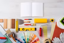 DIY training open manual with work tools, color swatches and painting rollers at bottom, top view