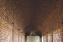 La réception est un espace très spectaculaire : treillis de pierre rouge, velours, lumière et ombre. Une longue table massive et ondulante en métal lisse ajoute une touche contemporaine.