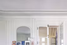 Sur la cheminée, vase en porcelaine à fleurs, The Conran Shop, fauteuil gris chiné au Marché Paul Bert. Sur la table basse, souvenirs de voyages et un plateau en cuivre algérien de sa grand-mère.