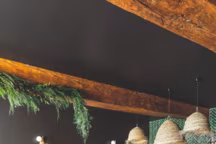 Dans une salle parquetée en chêne, murs colorés de la teinte "Off-Black" de Farrow&Ball, ancien bar repeint, suspensions du Maroc, appliques et fauteuils Opjet, tables Atmosphère&Bois, plantes de Nature Stabilisée et au fond, zelliges d'Ateliers Zelij.