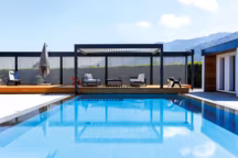 Installé dans le prolongement de la piscine, le modèle Bio 230 s'intègre parfaitement à la terrasse existante, avec son claustra
à lames d'aluminium. - Biossun