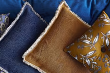 Plus d'info : coussins délavés à franges, plusieurs coloris disponibles, 17,99 euros ; petit coussin (à droite), 9,99 euros ; coussin à fleurs (à gauche), 15,99 euros, Monoprix.