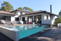 Piscine semi-enterrée réalisée en blocs à bancher, avec débordement sur parois vitrées, de forme trapèze, avec un escalier intérieur. 
Dim. : 8.30 x 3.80 x 2 m / Profondeur : 1.50 m (fond plat).Revêtement intérieur : membrane armée 150/100e coloris gris foncé.Filtration à sable. 2 pompes de filtration.Traitement de l'eau : électrolyseur au sel avec régulation pH. Chauffage : pompe à chaleur. Autres équipements : 1 projecteur. Appareil de nettoyage : balai hydraulique. Plages en bois composite. CARRE BLEU AGRETEC  A Artigues près Bordeaux (33); Architecte : Henri Blanchot