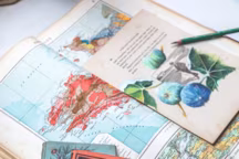 Livres datés de mi-XIXe à mi-XXe où l'artiste choisit le support en papier chiffon de ses illustrations. Derrière, Atlas universel Quillet de 1923, base future pour dessins de jonquilles et de morilles