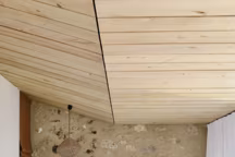 Côté maison, une chambre à l'esprit mansarde revêtue de peuplier, linge Maison de Vacances, tête de lit tissée en lin par Crearte.