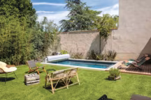 Piscine rectangulaire 5x3 m, liner gris anthracite, banquette toute largeur avec escalier d'angle, filtration PFI 181, margelles en pierres naturelles, plage en bois, couverture hors-sol automatique. A partir de 14.000 euros (piscine et pose, hors équipement). Desjoyaux.