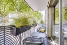 Sur un long balcon à Neuilly, le mobilier est léger et aérien (Réalisation agence Les Terrasses des Oliviers).