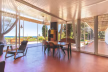 Grâce aux parois de verre, les espaces de vie, prolongés par un auvent habillé de bambou, jouissent d'une vue panoramique sur la mer et la baie.