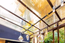 La verrière est dédiée aux arts de la table. Lignes épurées du Sofa " Murgi » ivoire et des chaises en corde nouée à la main. Nappes en lin et coton, vaisselle créative. Suspensions en verre soufflé à la bouche.