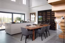 Cuisine ouverte avec grand ilot en finition cachemire, vitrine noire en verre fumé et salle à manger.