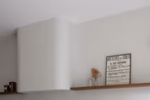 L'agence Bienvenues a choisi de transformer la hotte en un élément décoratif à part entière. Encadrée dans un conduit en placo arrondi, elle s'intègre au mur du fond, réduisant ainsi son aspect technique. Placée au centre de la pièce, elle structure l'espace tout en étant flanquée de tablettes de chaque côté. Réalisation agence Bienvenues