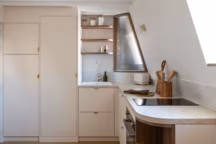 Petite cuisine ouverte en angle peinte en rose pâle. Réalisation Transition Interior Design