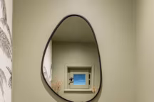 Un vert argile vient subtilement se conjuguer au papier peint noir et blanc pour créer un cocon enveloppant. Le lave-mains à été modernisé pour un WC plus tendance.