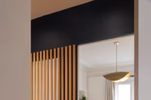 Le claustra en chêne vient délicatement séparer la chambre du couloir, laissant la lumière se propager dans cet espace de passage tout en maintenant une certaine intimité.